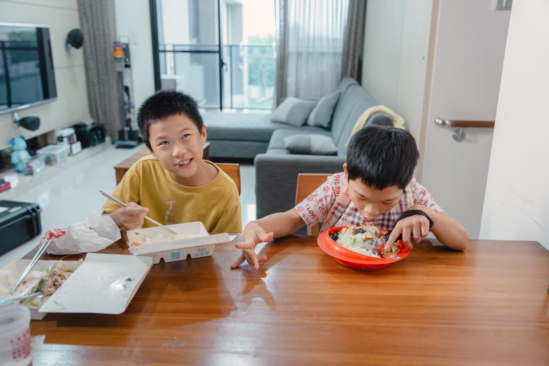 兩兄弟都是左撇子,弟弟在學校學習使用右手,把這個習慣帶回家裡,朋寯則是左手綁上輔助固定帶,使用可彎曲餐具與止滑吸盤的餐盤,各有千秋。